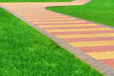 zemin olarak kaldırım taşları ve yeşil çimlerden yapılmış yürüyüş yolu, parlak güneş ışığı