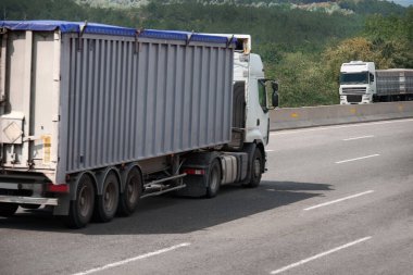 İki kamyon yolda birbirine doğru gidiyor, kargo taşımacılığı, nakliye konsepti.