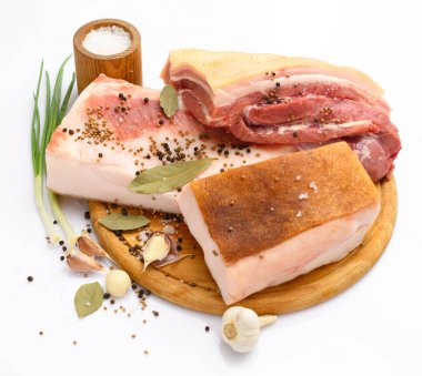 Kesme tahtasında tuzlu, baharatlı ve sarımsaklı çiğ domuz eti ve domuz yağı, beyaz arka plan.