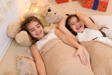 Kızlar yerde yatar, konuşur ya da uyur ve üzerlerini battaniyeyle örterler. Evin içi Noel ışıkları ve hediyelerle süslenir.