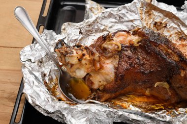 Fırında et ve kızarmış soğan, folyoda domuz eti ve ahşap arka plan, ev yemeği.