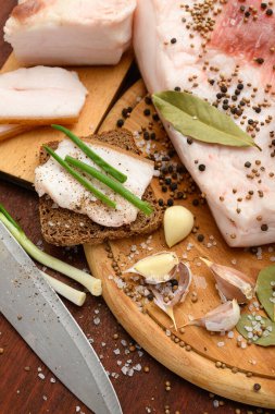 Kesme tahtasında tuzlu, baharatlı ve sarımsaklı çiğ domuz eti ve domuz yağı, koyu ahşap arka plan