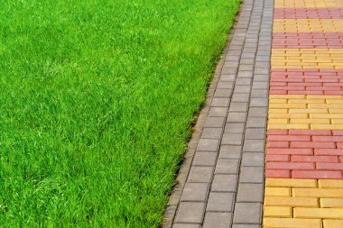 zemin olarak kaldırım taşları ve yeşil çimlerden yapılmış yürüyüş yolu, parlak güneş ışığı