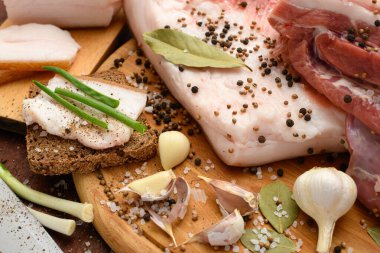 Kesme tahtasında tuzlu, baharatlı ve sarımsaklı çiğ domuz eti ve domuz yağı, koyu ahşap arka plan