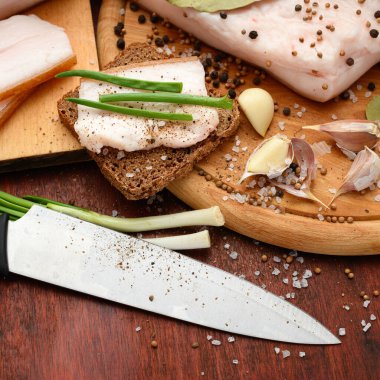 Kesme tahtasında tuzlu, baharatlı ve sarımsaklı çiğ domuz eti ve domuz yağı, koyu ahşap arka plan