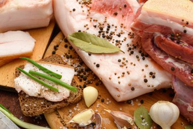 Kesme tahtasında tuzlu, baharatlı ve sarımsaklı çiğ domuz eti ve domuz yağı, koyu ahşap arka plan