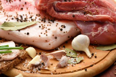 Kesme tahtasında tuzlu, baharatlı ve sarımsaklı çiğ domuz eti ve domuz yağı, koyu ahşap arka plan