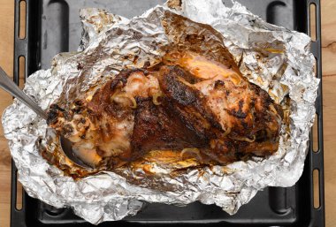 Fırında et ve kızarmış soğan, folyoda domuz eti ve ahşap arka plan, ev yemeği.