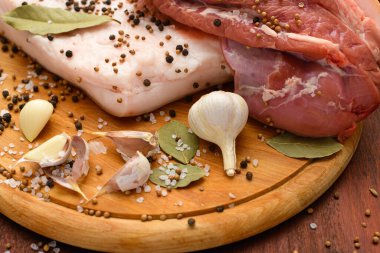 Kesme tahtasında tuzlu, baharatlı ve sarımsaklı çiğ domuz eti ve domuz yağı, koyu ahşap arka plan