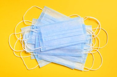 Sarı arka planda virüslere, mikroplara, morina ya da koronavirüse karşı solunum koruma maskesi ve diğer enfeksiyonlara karşı