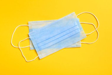 Sarı arka planda virüslere, mikroplara, morina ya da koronavirüse karşı solunum koruma maskesi ve diğer enfeksiyonlara karşı