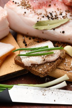 Kesme tahtasında tuzlu, baharatlı ve sarımsaklı çiğ domuz eti ve domuz yağı, koyu ahşap arka plan