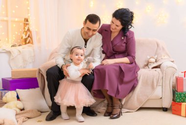 Bir aile portresi, bir aile portresi. Evdeki bir kanepede oturuyor. Işıklar ve hediyelerle süslenmiş.