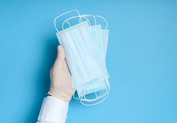 hands in medical gloves with a medical breathing mask on a blue background, health care prevention of coronavirus infection, as well as other viruses and pollution