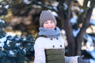 Genç kız kış ormanında poz veriyor, karla oynuyor.