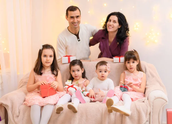 父母和孩子的全家福 坐在家里的沙发上 装饰着彩灯和礼物 — 图库照片