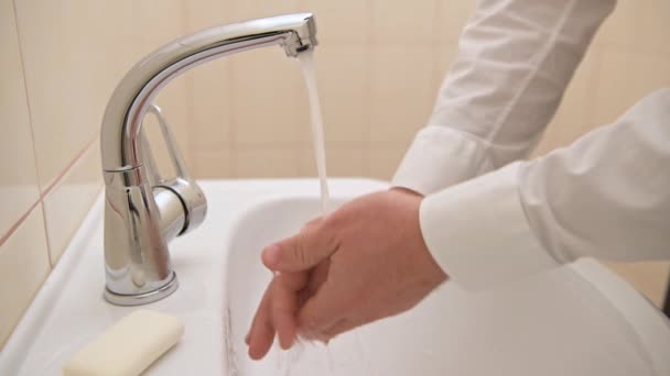 洗面台の水の下で石鹸やゲルで手を洗う 清潔と衛生 白いシャツを着た男性の手 — ストック動画