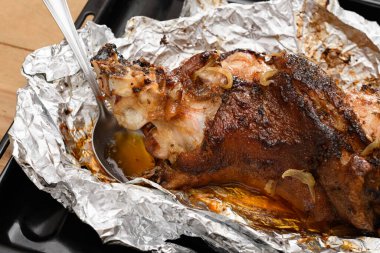 Fırında et ve kızarmış soğan, folyoda domuz eti ve ahşap arka plan, ev yemeği.