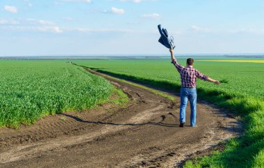 Bir çiftçi olarak tarlada ekose gömlek ve kot giymiş genç lahanaların, buğday, arpa veya çavdar mahsullerinin veya diğer tahılların, tarım ve tarım kavramının tadını çıkaran bir adam.