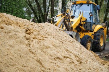 Traktör veya buldozer inşaat için kum yığınıyla çalışır.