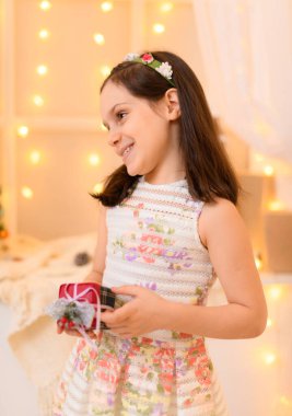 Evin içinde ışık ve bayram hediyeleriyle süslenmiş bir kız çocuğunun portresi.