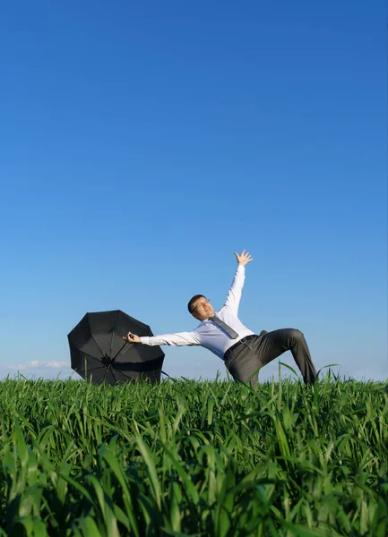 Geschäftsmann Posiert Mit Regenschirm Auf Einem Feld Fällt Ein Krisenbegriff — Stockfoto