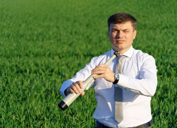 사업가가 물컵을 포즈를 취하고저 잔디와 하늘을 배경으로 무엇인가를찾습니다 — 스톡 사진