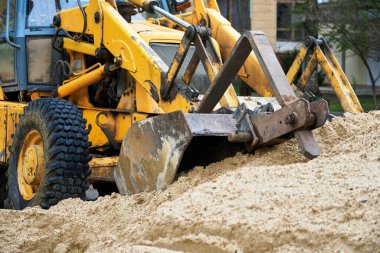 Traktör veya buldozer inşaat için kum yığınıyla çalışır.