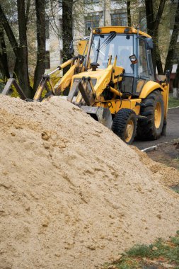 Traktör veya buldozer inşaat için kum yığınıyla çalışır.