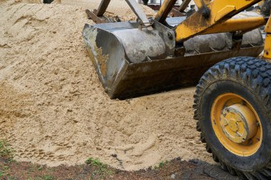 Traktör veya buldozer inşaat için kum yığınıyla çalışır.