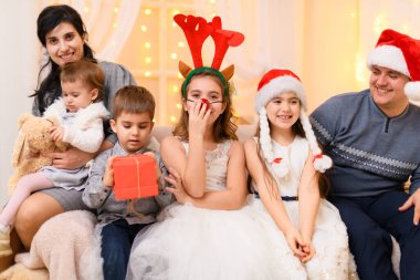 Mutlu büyük aile portresi. Noel ışıkları ve hediyelerle dekore edilmiş, Noel Baba şapkası takmış aileler ve çocuklar. Yeni yıl kutlamaları için.