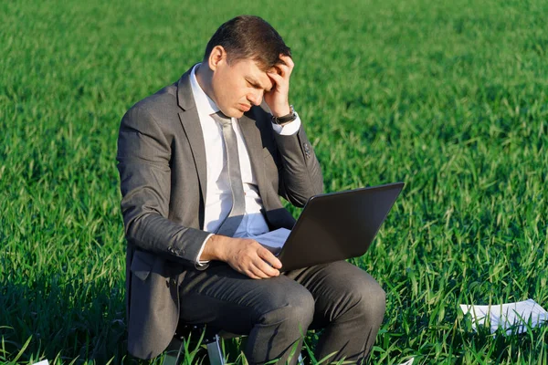 businessman works in a green field, freelance and business concept, green grass and blue sky as background