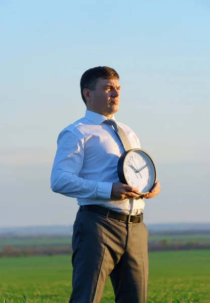 Ein Geschäftsmann Hält Eine Bürouhr Auf Einem Feld Mit Grünem — Stockfoto