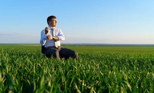 ビジネスマンはフィールドのオフィスチェアに座って 背景に自由とビジネスの概念 緑の草と青空 — ストック写真