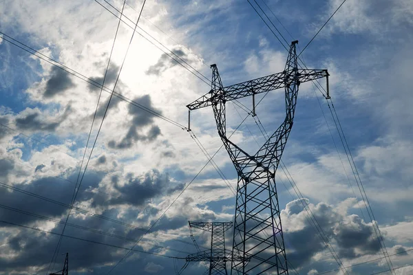 High-voltage electric lines, towers and industrial infrastructure against the blue sky