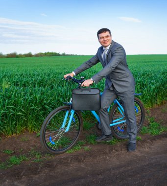 Bisikletli bir iş adamı yeşil çimen tarlasında poz veriyor - iş konsepti özgürlük, tatil ya da serbest çalışma. Güzel bahar doğası.