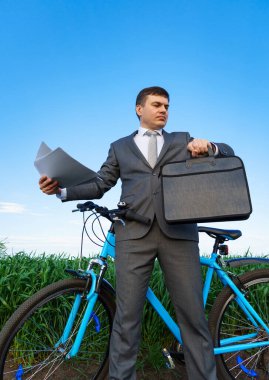 Bisikletli bir işadamı yeşil çimenlik alanda belgelerle çalışır - iş konsepti özgürlük, tatil ya da serbest çalışma. Güzel bahar doğası.