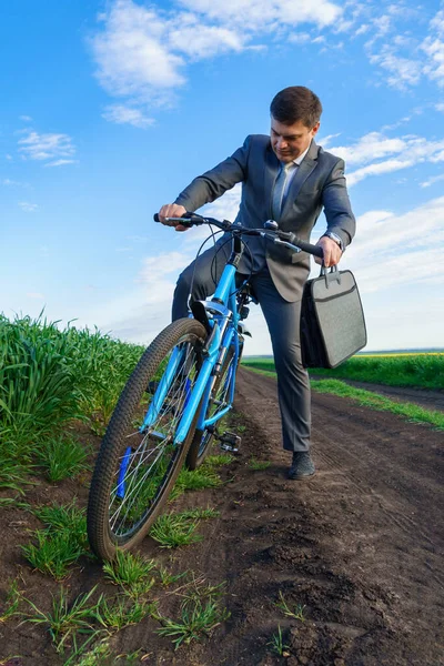 ビジネスマンは緑の芝生のフィールドで自転車に乗る 休暇やフリーランスのためのビジネスコンセプト 美しい春の自然 — ストック写真