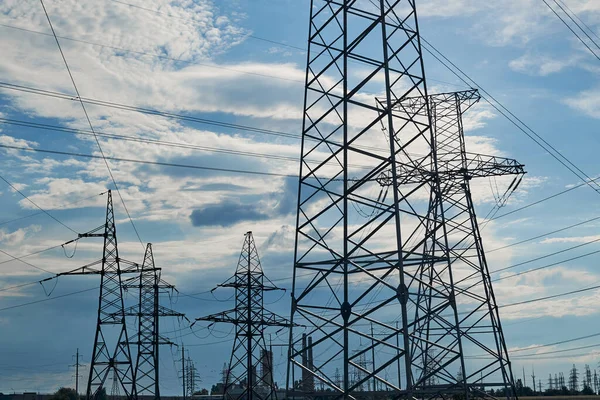 Mavi gökyüzüne karşı yüksek voltajlı elektrik hatları, kuleler ve endüstriyel altyapı