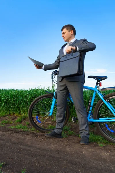 骑自行车的商人与绿草领域的文件打交道 度假或自由职业的商业概念 美丽的春天 — 图库照片