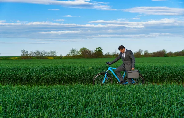 ビジネスマンは緑の芝生のフィールドで自転車に乗る 休暇やフリーランスのためのビジネスコンセプト 美しい春の自然 — ストック写真