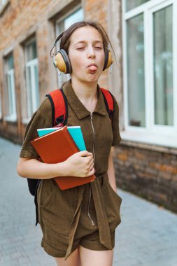 Okula giden genç bir liseli kız. O, kulaklıkla müzik dinliyor ve bir kitap tutuyor. Eğitim ve okul konseptine dönüş