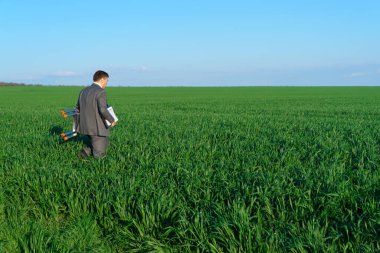 İş adamı yeşil bir alanda poz veriyor. Belge ve merdiven, serbest ve iş konsepti, arka plan olarak yeşil çimen ve mavi gökyüzü ile devam ediyor.