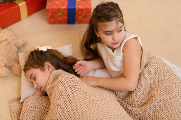 女孩子们躺在地板上聊天或睡觉 用毛毯盖住她们自己 用节日彩灯和礼物装饰她们的家 — 图库照片