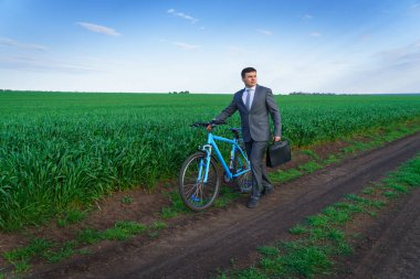 Bisikletli bir iş adamı yeşil çimen tarlasında poz veriyor - iş konsepti özgürlük, tatil ya da serbest çalışma. Güzel bahar doğası.