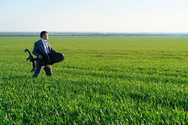 ビジネスマンは仕事 フリーランス ビジネスのコンセプト 緑の草と青空を背景にオフィスチェアを持っています — ストック写真