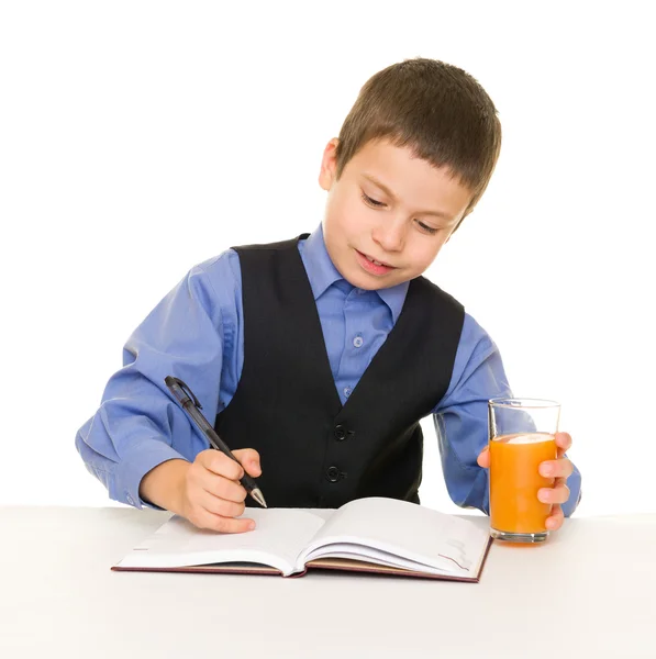 Colegial bebe jugo en un escritorio con diario y pluma — Foto de Stock