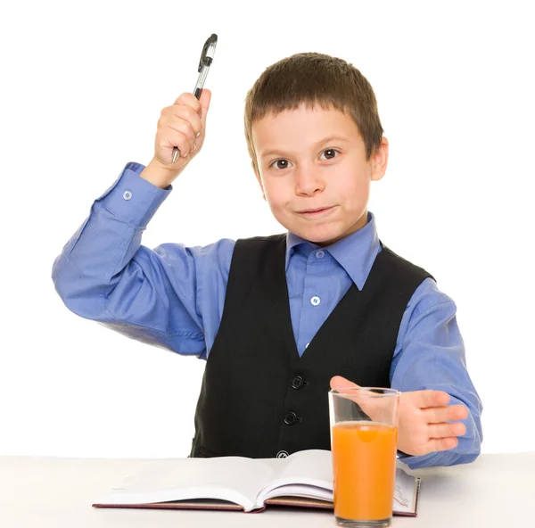 Schoolboy drinks juice at a desk with diary and pen — Stock Photo, Image