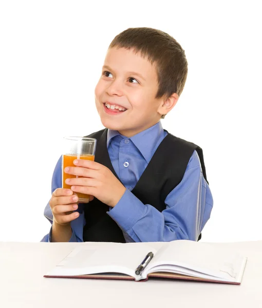 Scolaretto beve succo a una scrivania con diario e penna — Foto Stock