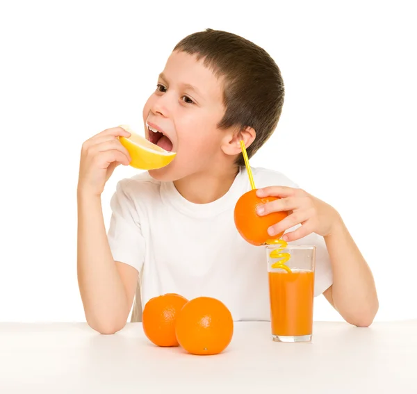 Menino beber suco de laranja com uma palha — Fotografia de Stock
